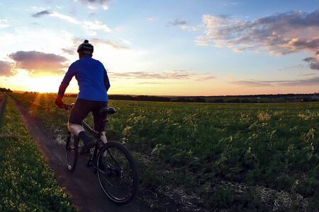 cyclist rides a bicycle on a track at sunsetの写真素材