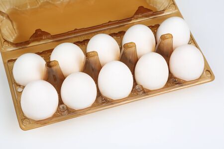 white chicken eggs in a tray on a white backgroundの写真素材