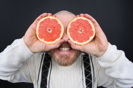 smiling bearded man with a cut grapefruit in his hands
の写真素材