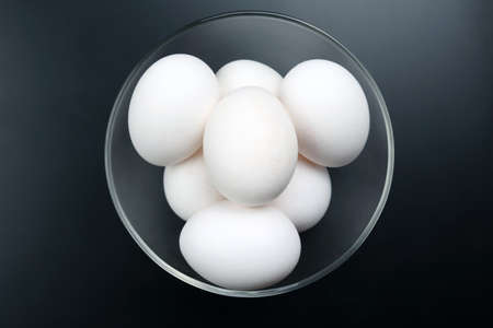 white chicken eggs lying on the plate on a dark backgroundの写真素材