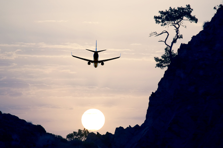 passenger jet plane flying in the evening sky at sunsetの写真素材