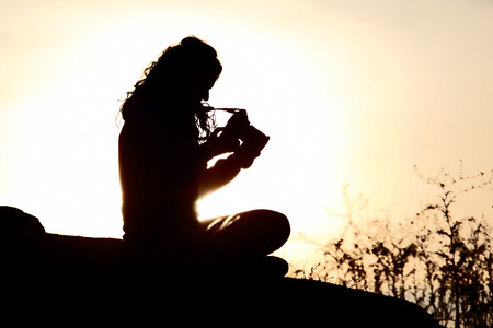 silhouette of people taking pictures against the setting sunの写真素材