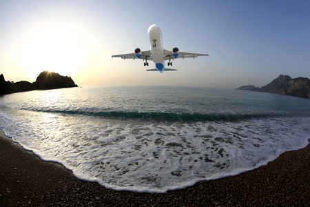 Passenger plane is landing on the background of the sea shore at dawnの写真素材