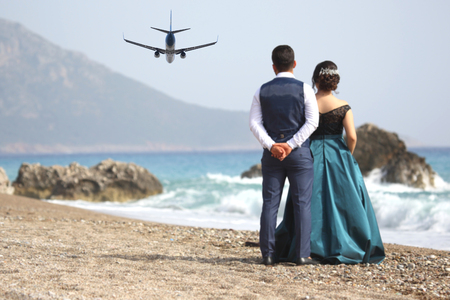 man and a woman looking at the departing passenger plane on the beachの写真素材