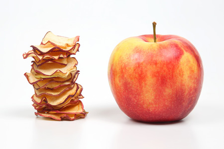 Fresh Apple and a stack of dried Apple slices on white background