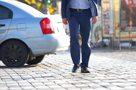 business man crossing the road at a pedestrian crossing on the pavementの写真素材