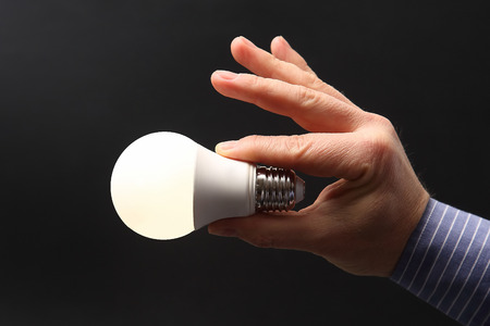 human hand holding luminous led lamp on dark background
