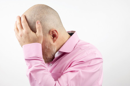 sad man with hands closed face on white backgroundの写真素材