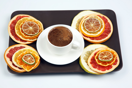Black coffee in a white Cup surrounded by citrus dried fruitsの写真素材