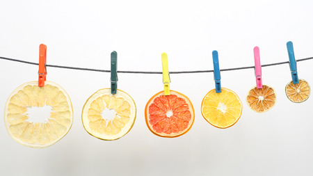 dried pieces of citrus fruits hang on clothespinsの写真素材