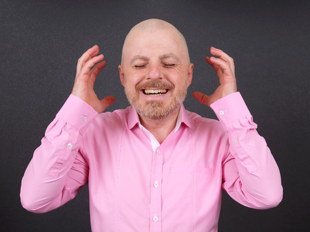 Portrait of a happy bearded man in a shirt with arms raised