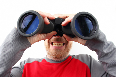 Bearded man looking through binoculars on white backgroundの写真素材