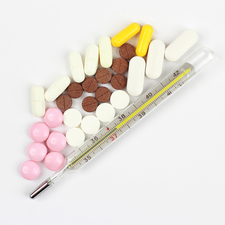 thermometer and medical pills on white background. pharmacology, medicine and treatment of diseases