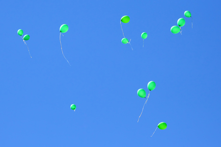 many green balloons flying in the blue sky. Items to celebrate eventsの写真素材