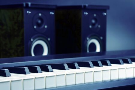 two stereo audio speakers and piano keys closeup on dark background. sound and musicの写真素材