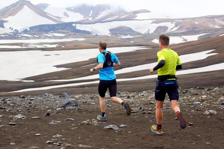 Two athlete runners run a mountain marathon in the snowy terrain of Landmannalaugar. Icelandの写真素材