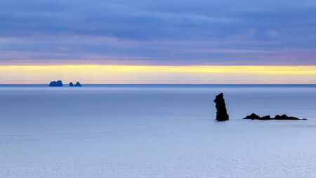 Rocks in the ocean against the evening skyの写真素材