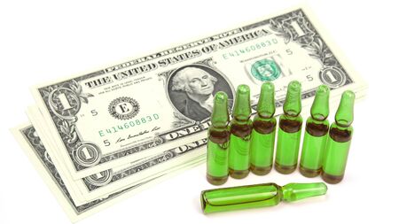 seven medical glass ampoules for injection on the background of dollar banknotes. medical business and healthの写真素材
