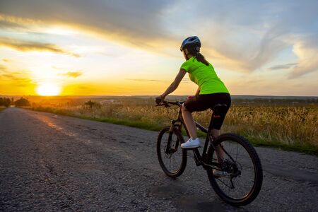 Beautiful girl cyclist riding a bike on the road towards the sunset. Nature and recreation. Hobbies and sports
の写真素材