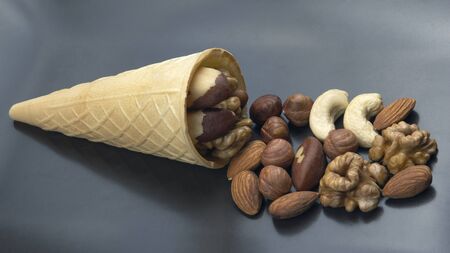 Different types of nuts in a waffle cone on a gray background. Healthy and protein foodの写真素材