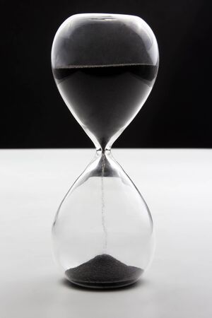 Hourglass on a dark white background. Time is money. Business solutions in time.の写真素材