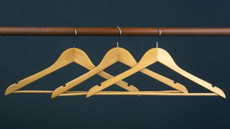 Empty wooden clothes hanger hanging on a dark background. Accessories and items for storing clothes.の写真素材