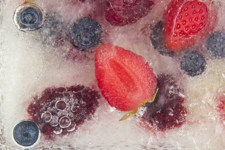 different juicy berries frozen in ice. useful vitamin healthy foodの写真素材