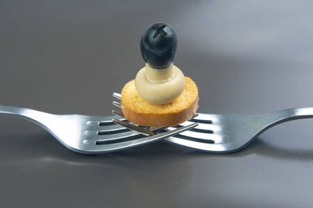 Olives, bread, mushrooms on a fork close-up on a gray background. food and vegetables. diet and...