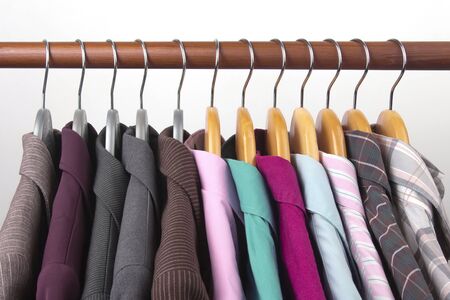 Different women's office classic jackets and shirts hang on a hanger for storing clothes. The choice of style of fashionable clothesの写真素材