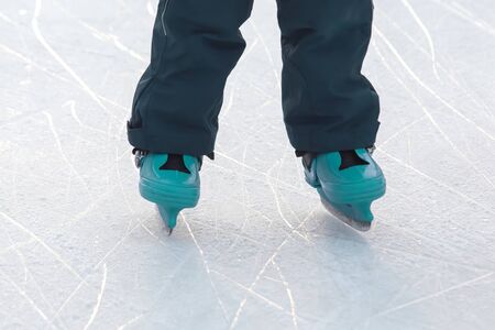 feet on the skates of a person rolling on the ice rink. Hobbies and sports. Vacations and winter...