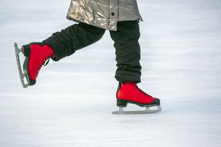 feet in red skates on an ice rink. Hobbies and sports. Vacations and winter activities.