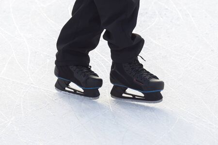 Legs of a man skating on an ice rink. Hobbies and sports. Vacations and winter activities.