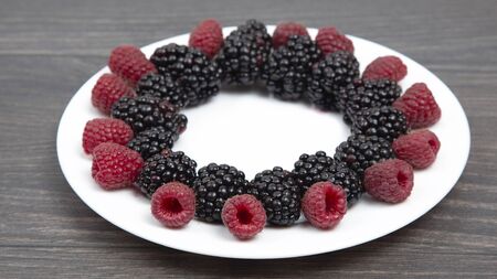 raspberries and blackberries on a white plate. Vitamin and Diet Food