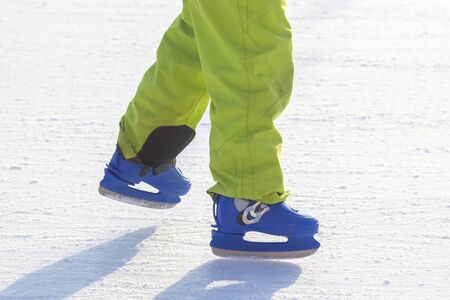 legs of a man in blue skates rides on an ice rink. hobbies and leisure. winter sports