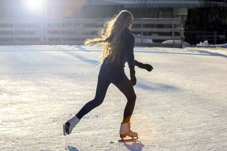 Girl with long hair skates on an ice rink in the sunlight and glare. Sport and hobbies. Holidays and winter fun
の写真素材