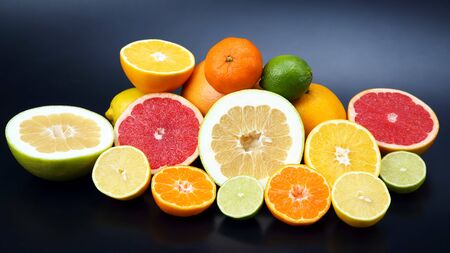 cut pieces of different citrus fruits on dark backgroundの写真素材