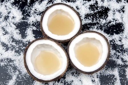 cut fresh coconut with real coconut milk on a background of coconut flakes. vitamin fruits. healthy...