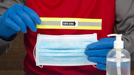 male hands in protective gloves show a medical mask and a table with the inscription sos on the...