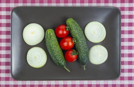 Fresh cucumbers and tomatoes and onions on a gray plate. vitamins and light breakfast
の写真素材