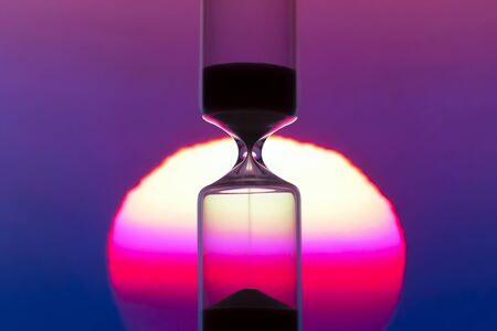 Hourglass on the background of a sunset. The value of time in life. time measuring tool. An...