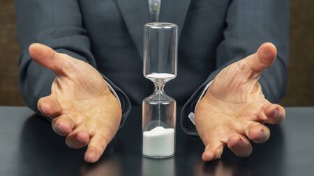 hourglass next to the hands of a business man. business time. success goals planning