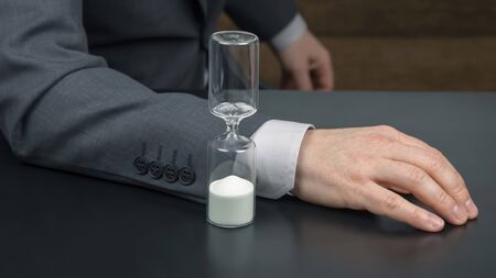 hourglass next to the hands of a business man. business time. success goals planning