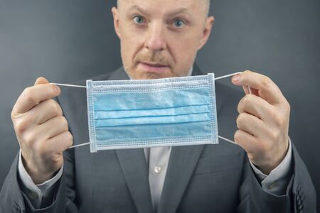 man in a business suit suggests using a medical protective mask in quarantine during an epidemic of coronavirus.の写真素材