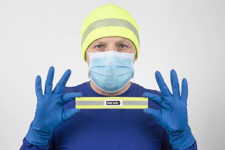 man in a medical mask and protective gloves holds a sign with the inscription sos info. virus...