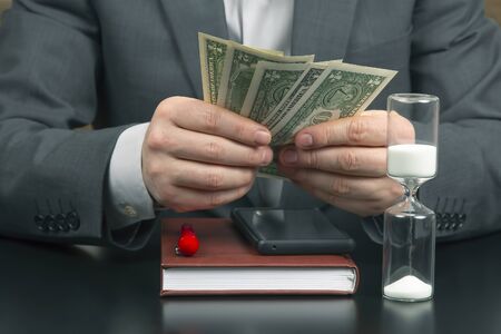 business man in the office counts money on a background of sundials. business and remuneration.