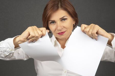 Beautiful business woman tearing white paper in halfの写真素材