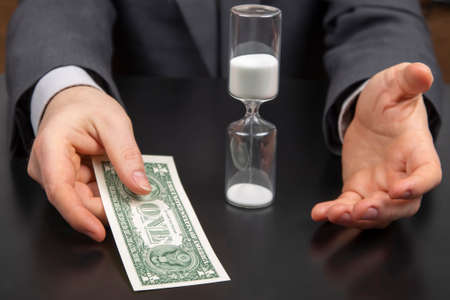 money and hourglass on the background of a business man. distribution of time for work. time to make...