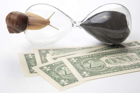 snail crawls on an hourglass against the background of money. speed and stability in increasing...