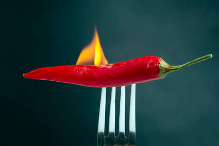 red hot peppers on a fork in real fire. vegetative vitamin foodの写真素材