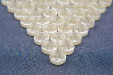 Plastic shiny buttons for clothes on a fabric background. Fashion and clothing. Factory industry.